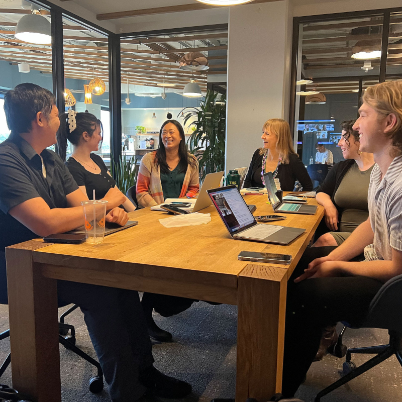 Tiao Properties Team in conversation at wooden conference table